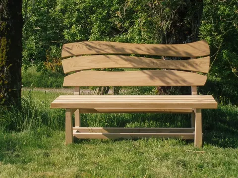 Bangku kayu dengan sandaran di atas rumput.