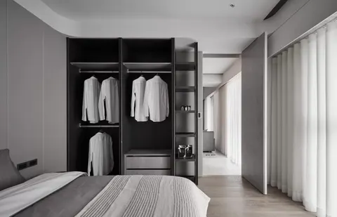 Lemari pakaian terbuka berwarna gelap di kamar tidur.