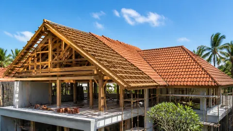 Rumah dalam pembangunan dengan rangka kayu dan sebagian atap genteng terpasang