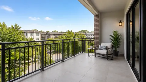 Balkon berlantai ubin dengan pagar bilah vertikal dan area tengah tanpa furnitur